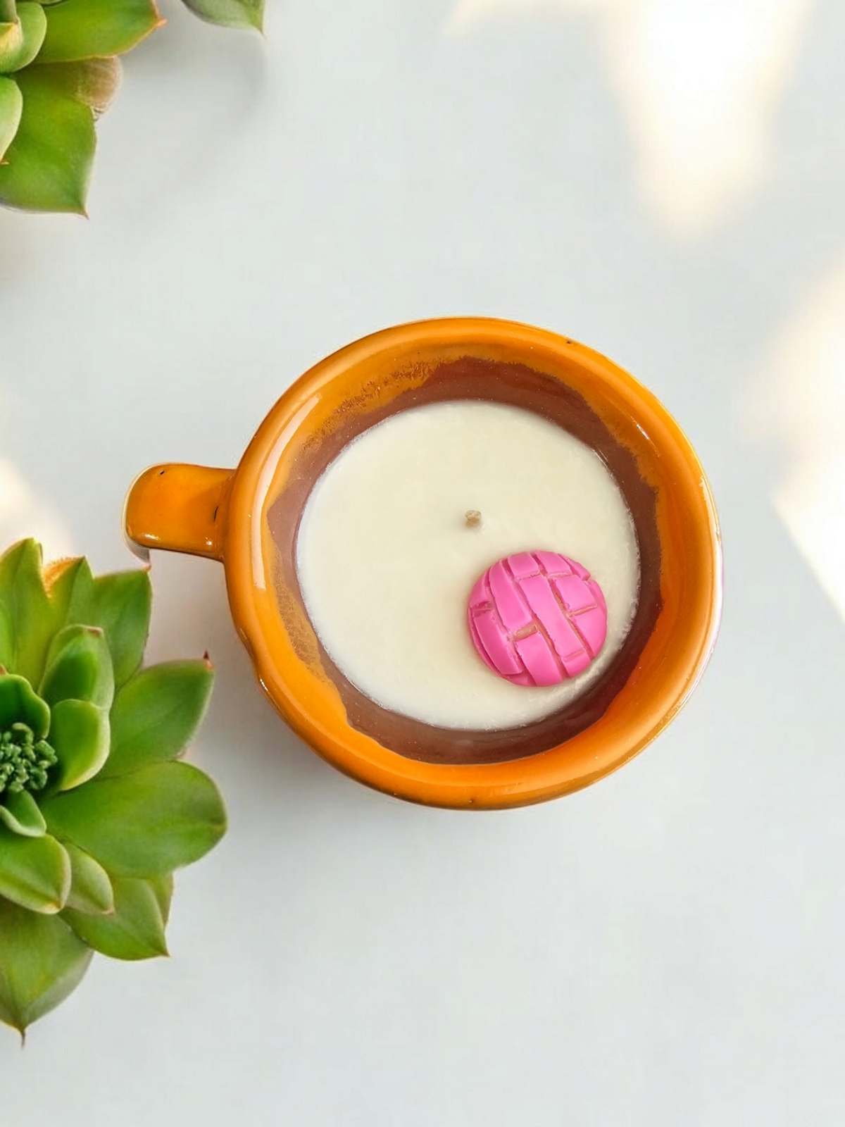 The Vela Lady soy wax candle in a traditional handmade Mexican barro taza mug with a decorative pink concha topper.
