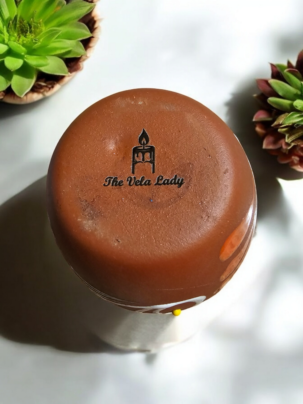 The Vela Lady El Venado Loteria cantarito candle base showing the brand logo on handmade Mexican barro pottery