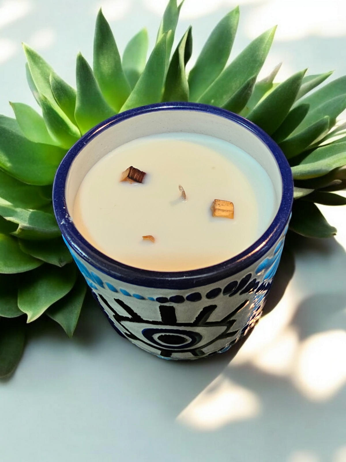 The Vela Lady Buenas Vibras soy wax candle in a blue and white hand-painted Mexican Talavera evil eye tumbler vessel.