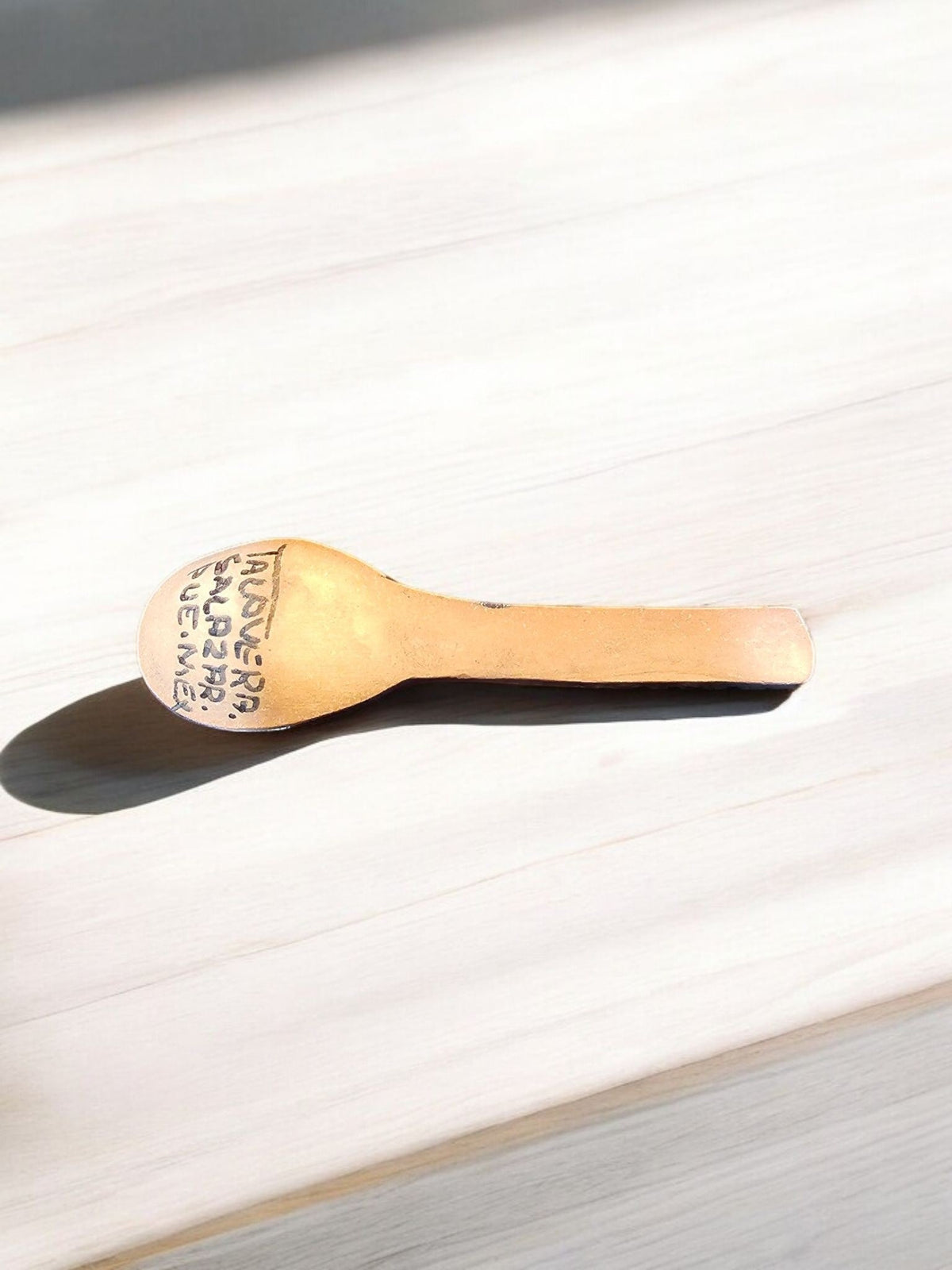 The Vela Lady handcrafted ceramic spoon with Talavera Salazar Puebla Mexico inscription on a light wooden surface