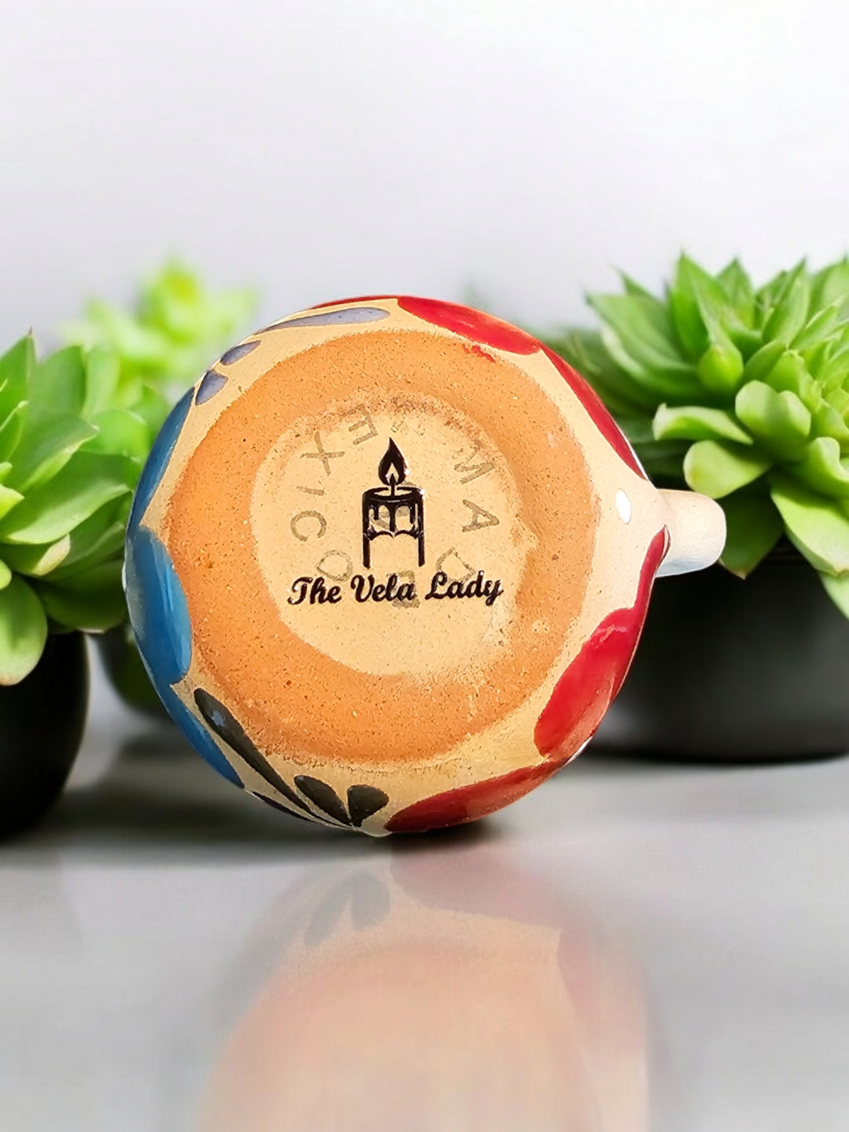 The Vela Lady handmade Mexican barro tazita shot mug with hand-painted colorful floral patterns on the base