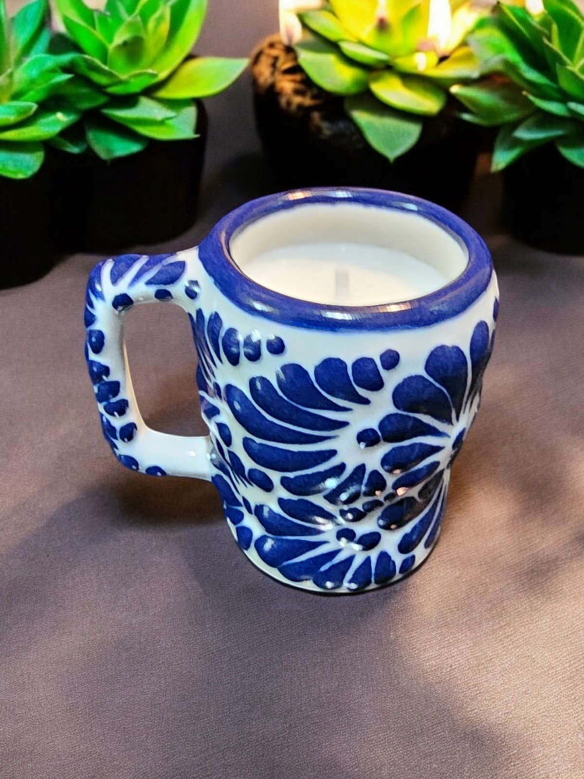 The Vela Lady blue and white hand-painted Talavera ceramic shot glass candle with a soy wax fill.
