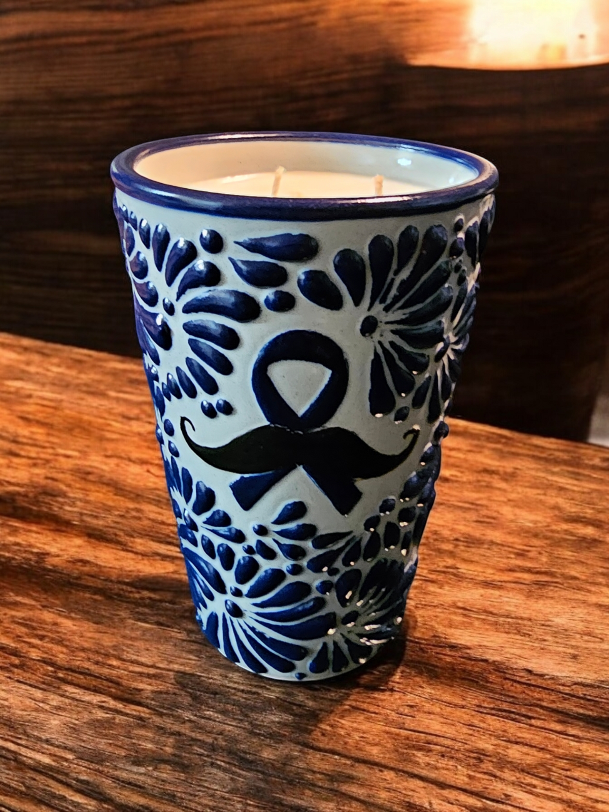 The Vela Lady soy wax candle in a blue and white hand-painted Mexican Talavera pottery vessel with mustache motif.