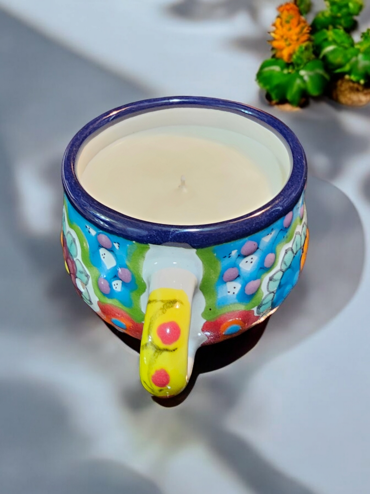 The Vela Lady La Catrina Talavera mug candle with hand-painted floral patterns and soy wax in a vibrant ceramic vessel.
