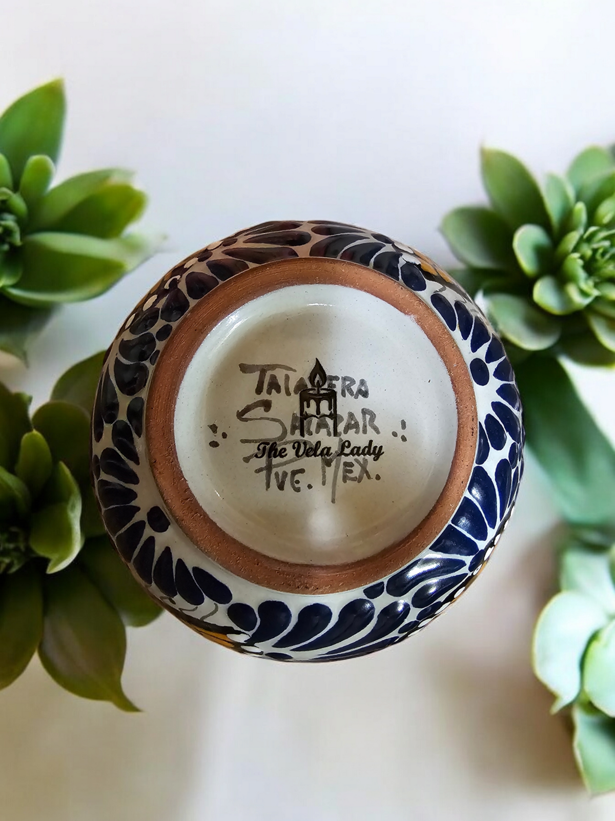 Bottom view of The Vela Lady Talavera barro salsa bowl candle showing Talavera Salazar artisan stamp and blue floral pattern