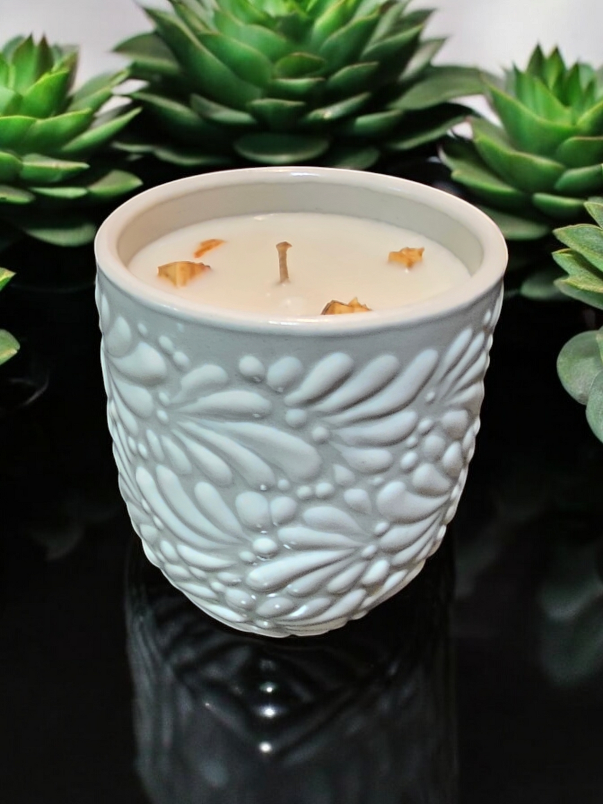 The Vela Lady Buenas Vibras soy wax candle in a white embossed Mexican Talavera tumbler with Palo Santo wood chunks.