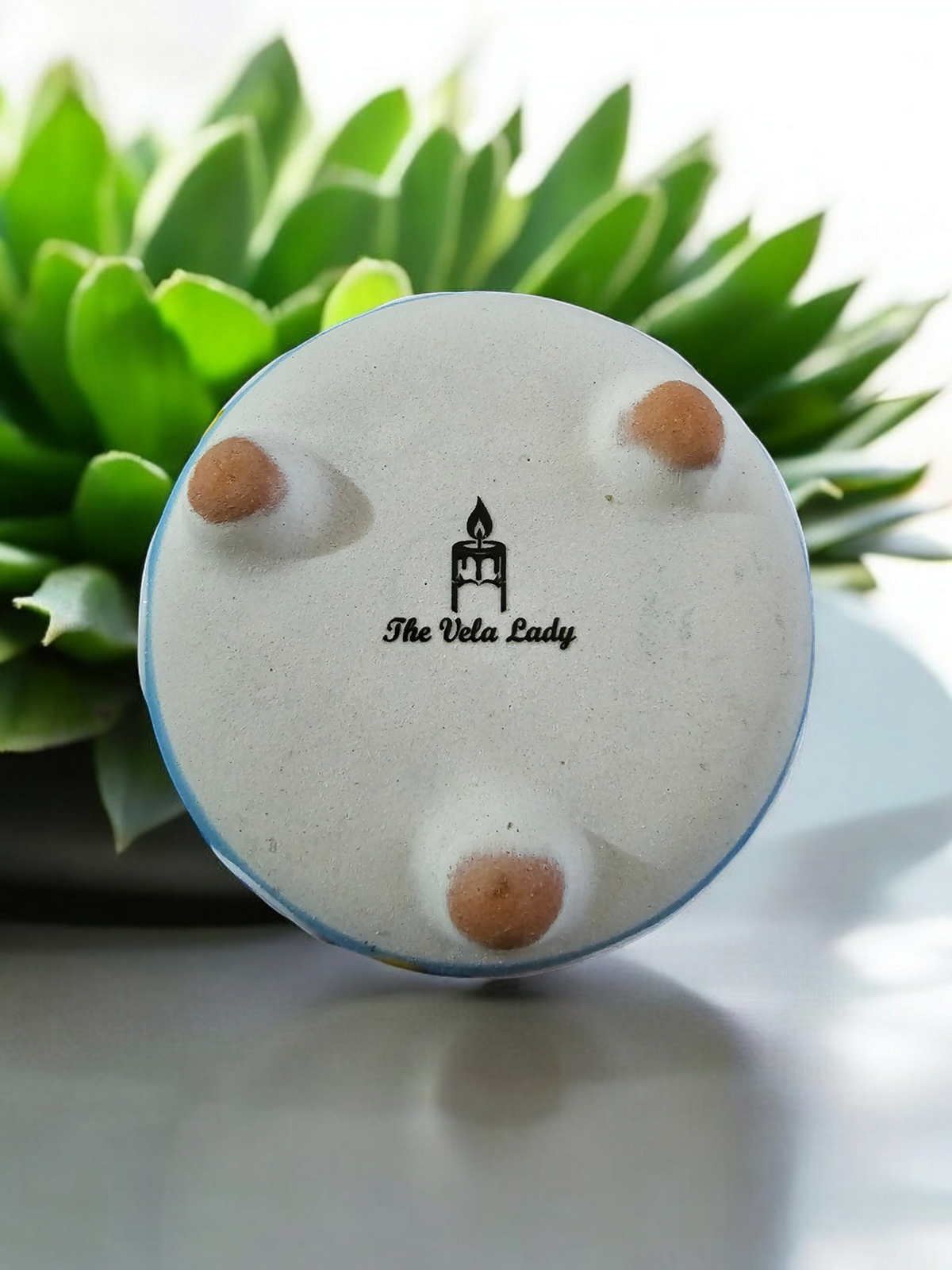 The Vela Lady handmade light blue barro salsa bowl candle base with three feet and brand logo on the bottom