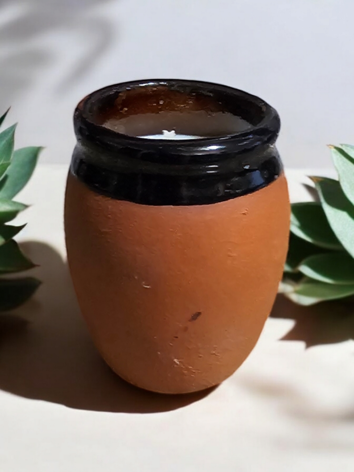 The Vela Lady El Pajaro Cantarito soy candle in a handmade Mexican barro clay shot glass vessel with a black rim.