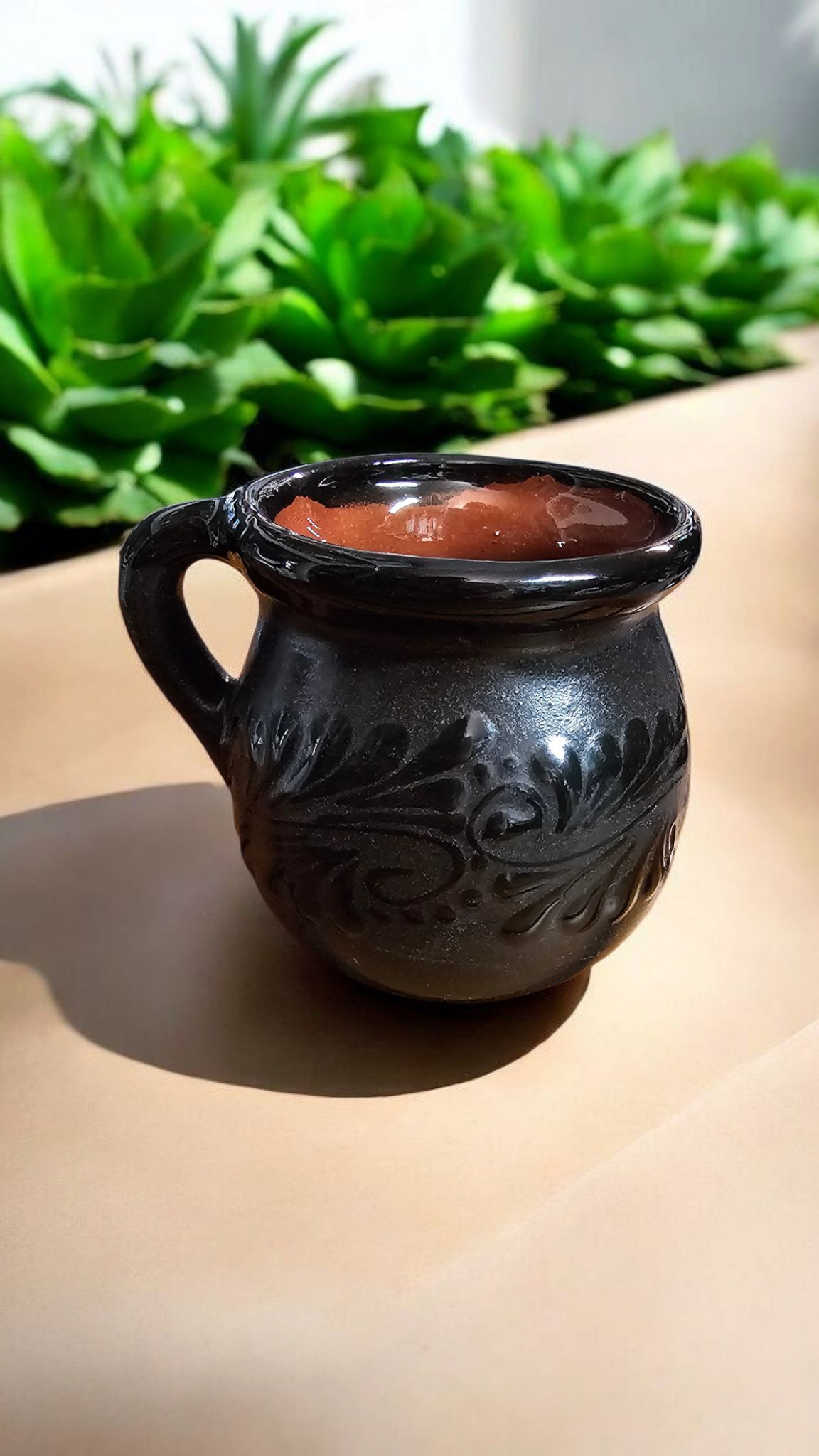 The Vela Lady Papacito Collection black Mexican barro pottery mug candle with intricate embossed floral patterns.