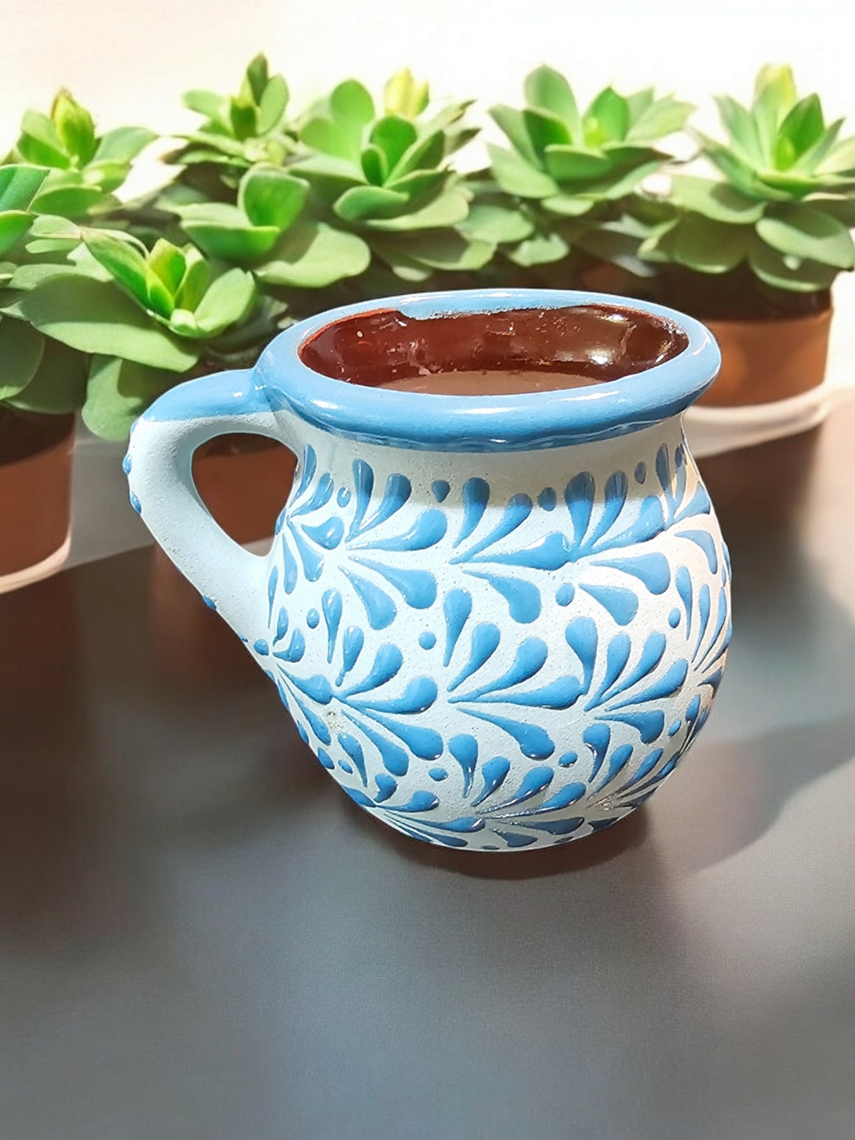The Vela Lady blue hand-painted Mexican lead-free ceramic barro mug candle with intricate floral patterns and premium soy wax filling.