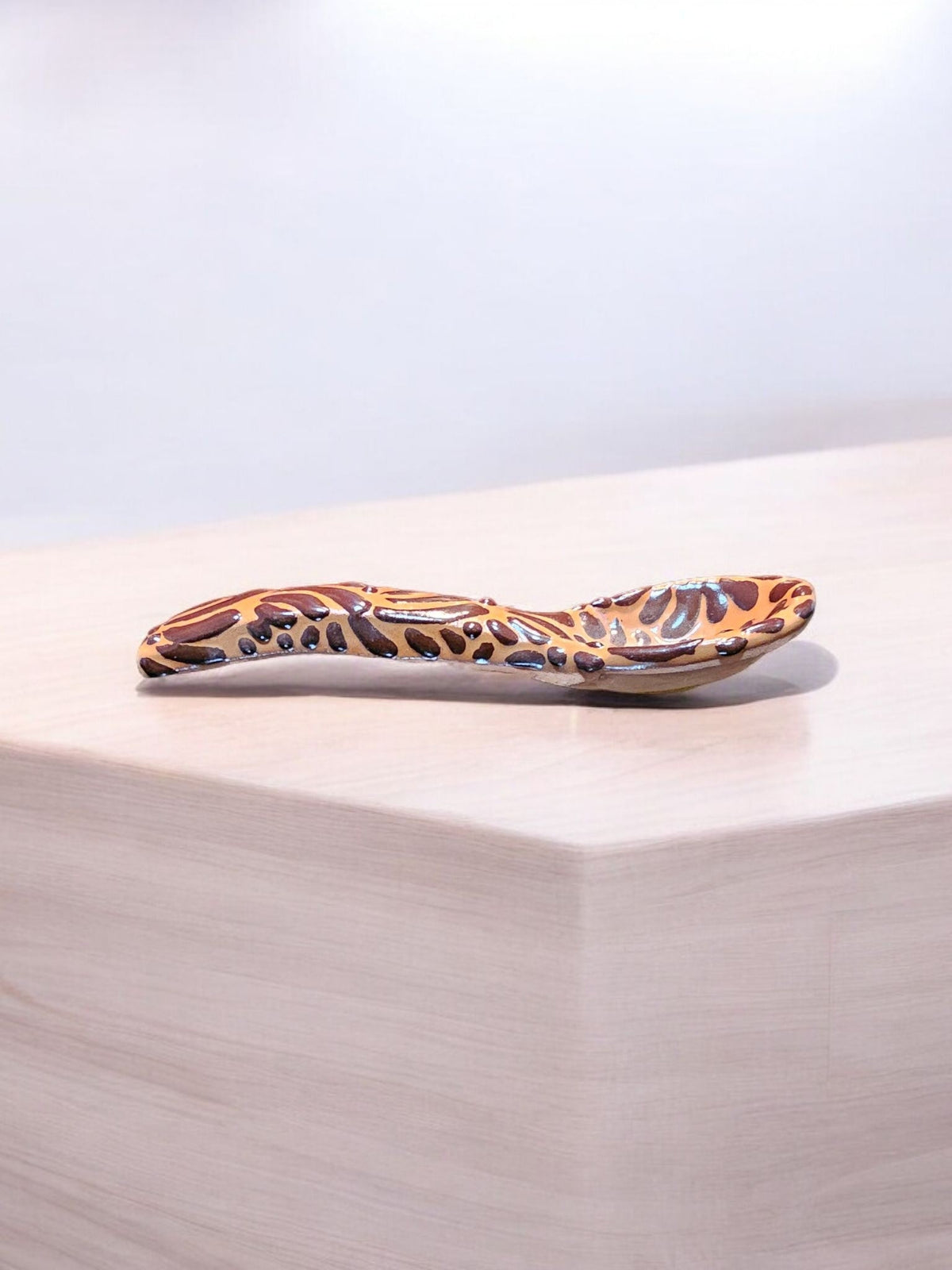 The Vela Lady handcrafted brown Talavera spoon with intricate butterfly patterns, matching the salsa bowl collection.