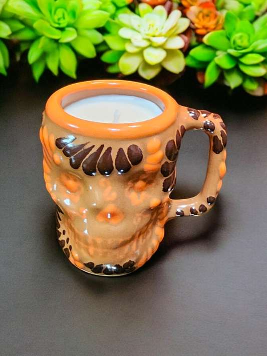 The Vela Lady Calavera shot glass candle in orange and brown lead-freeTalavera ceramic pottery with hand-poured premium soy wax.