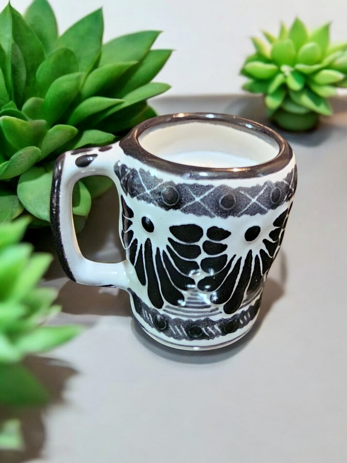 The Vela Lady Calavera shot glass soy candle with black and white hand-painted Mexican Talavera pottery design.