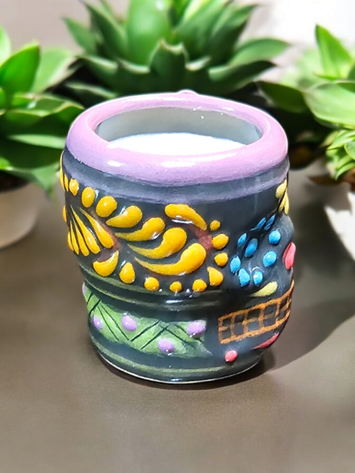 The Vela Lady Calavera shot glass candle with hand-painted Mexican Talavera design in grey, yellow, and pink.