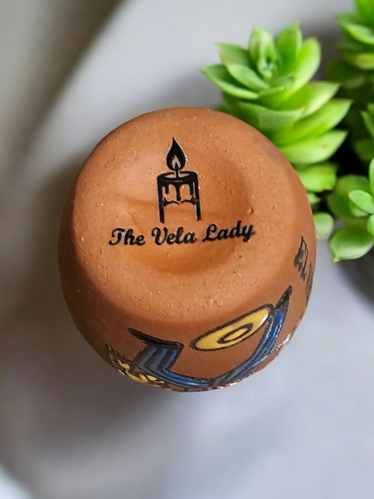 The Vela Lady El Catrin Loteria cantarito candle in handmade Mexican barro pottery, viewed from above.