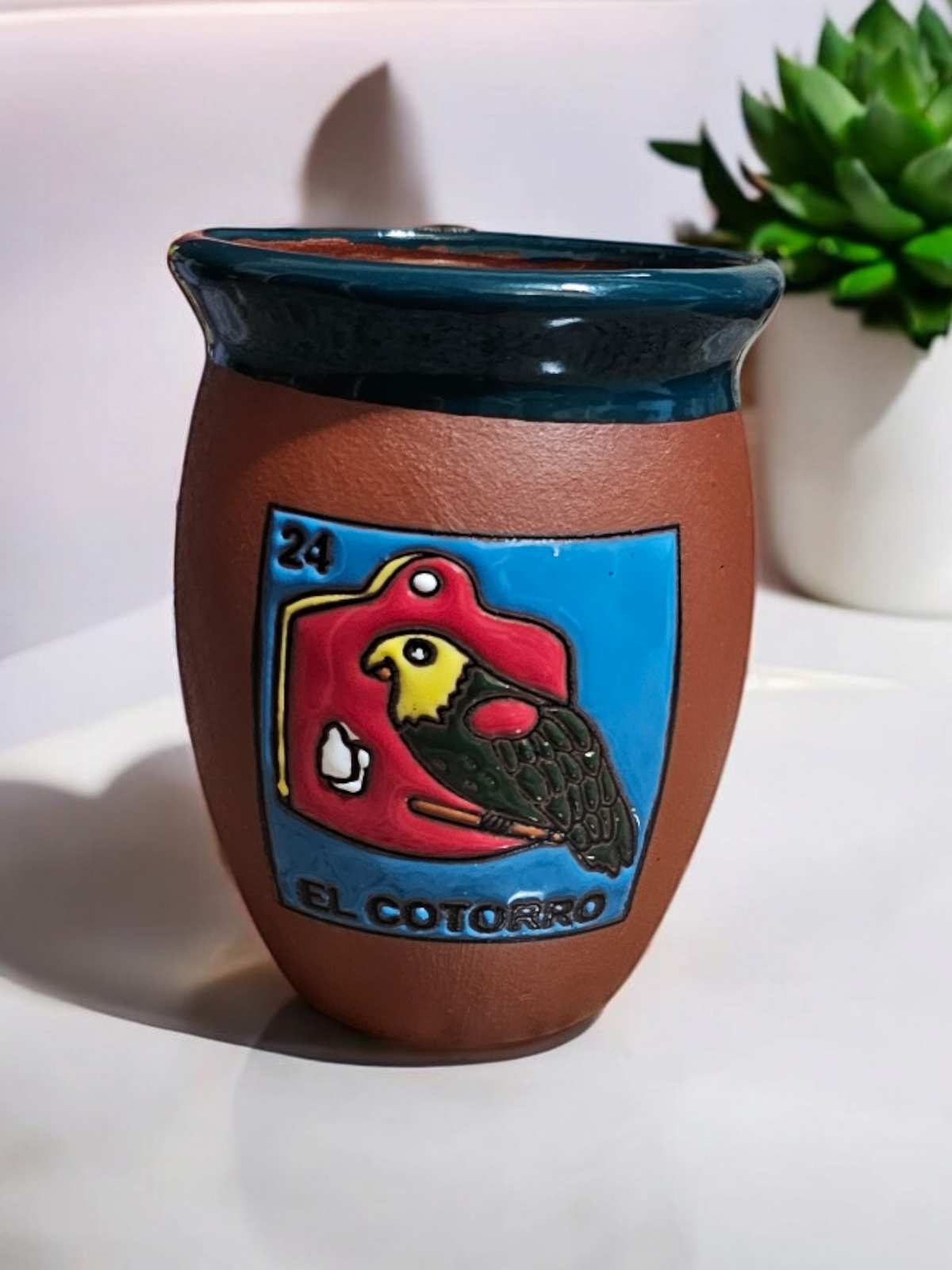 The Vela Lady El Cotorro Loteria cantarito soy candle in handmade Mexican barro pottery with a hand-painted parrot.