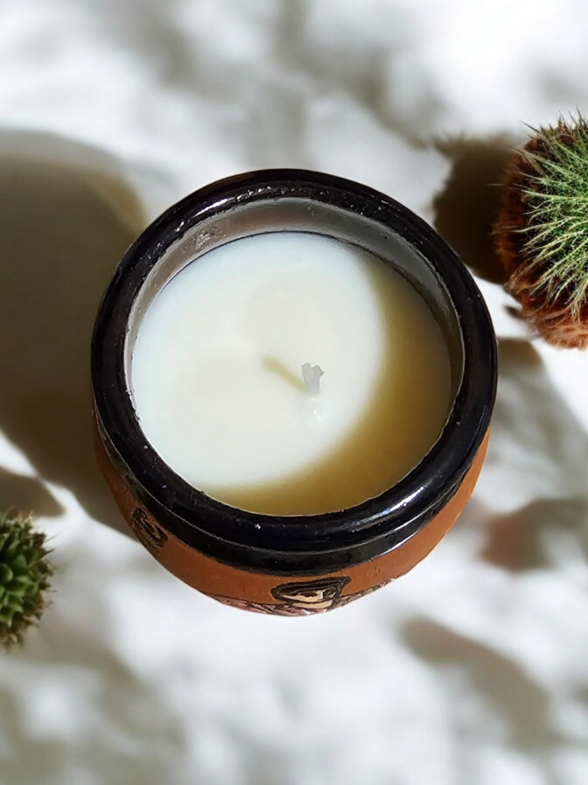 The Vela Lady El Pajaro Cantarito soy wax candle in a handmade Mexican barro shot glass vessel with a mimosa scent.