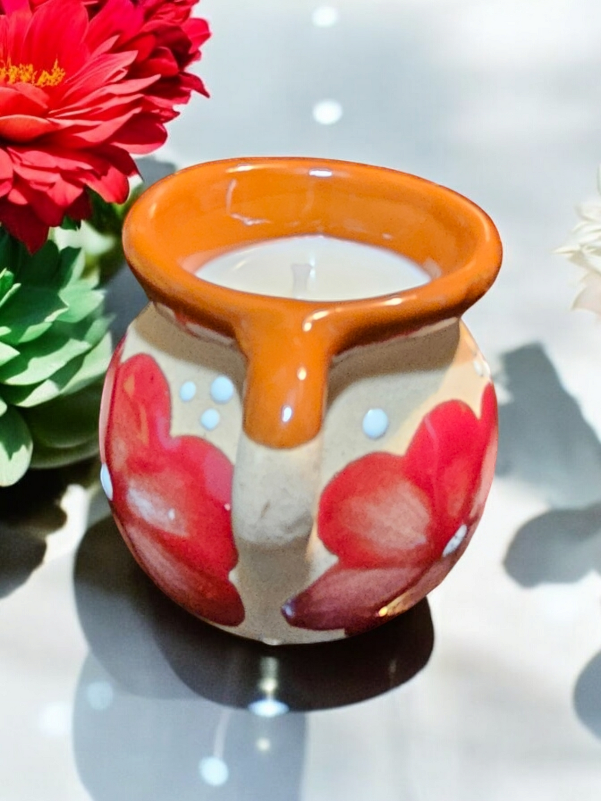 The Vela Lady handmade Mexican barro tazita shot glass candle with hand-painted red floral design and soy wax