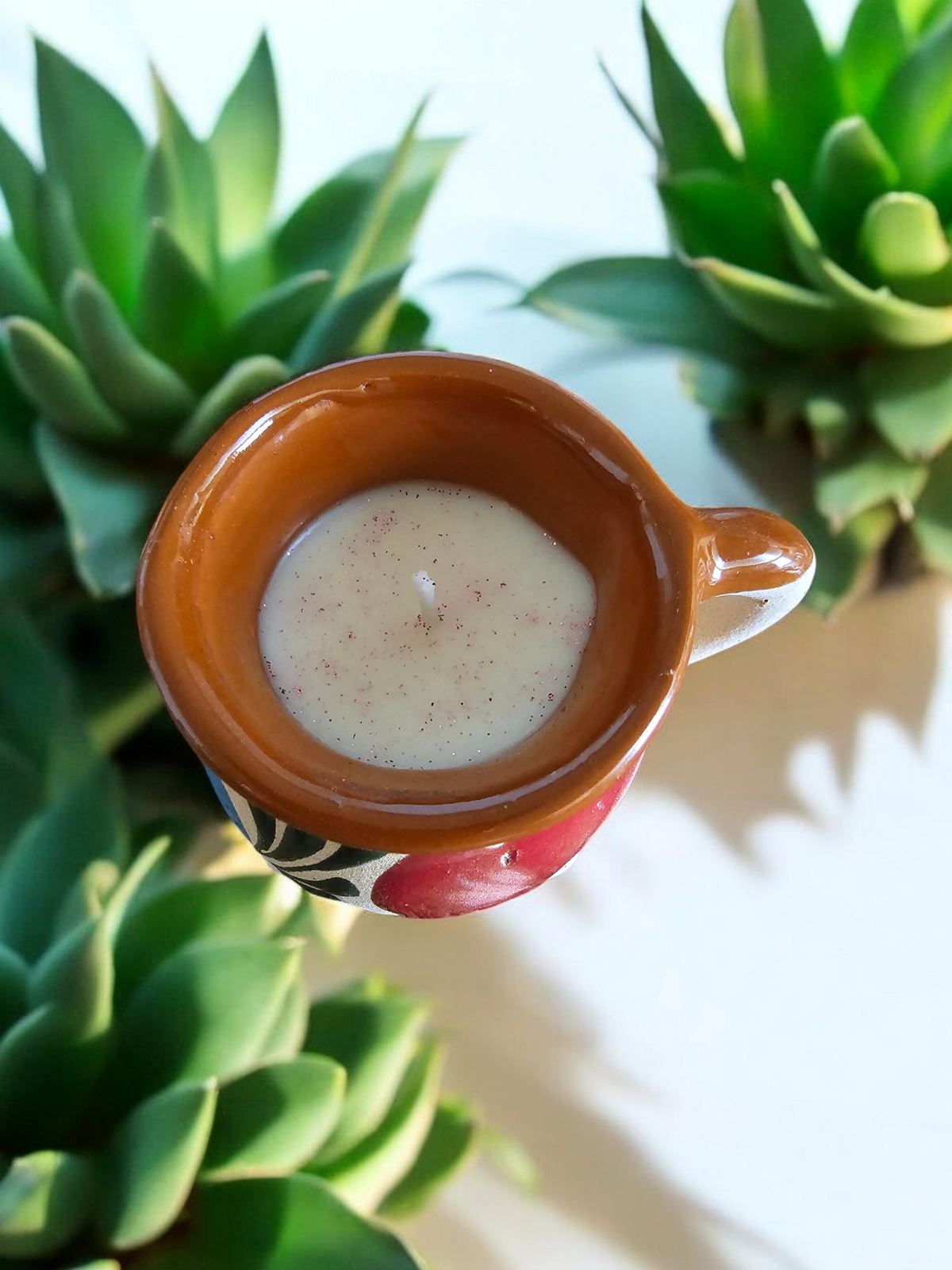The Vela Lady handmade Mexican barro tazita shot candle with soy wax, featuring a colorful hand-painted design.