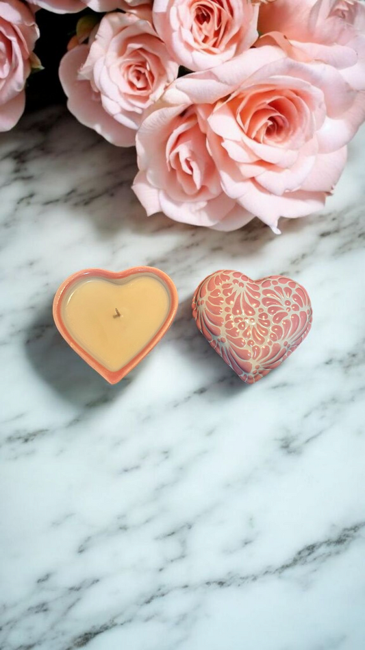 The Vela Lady heart-shaped pink Talavera ceramic candle and matching lid on a marble surface with pink roses