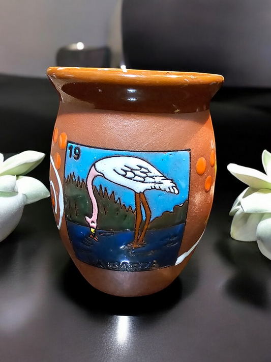 The Vela Lady La Garza Loteria cantarito premium soy wax candle in a handmade Mexican barro clay vessel with a heron illustration.