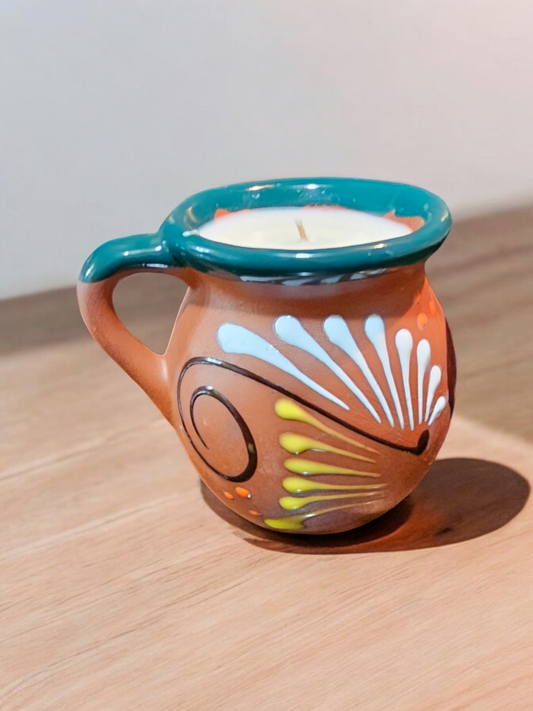 The Vela Lady handmade Mexican lead free barro mug premium soy wax candle with dark floral hand-painted details and soy wax on a wooden surface