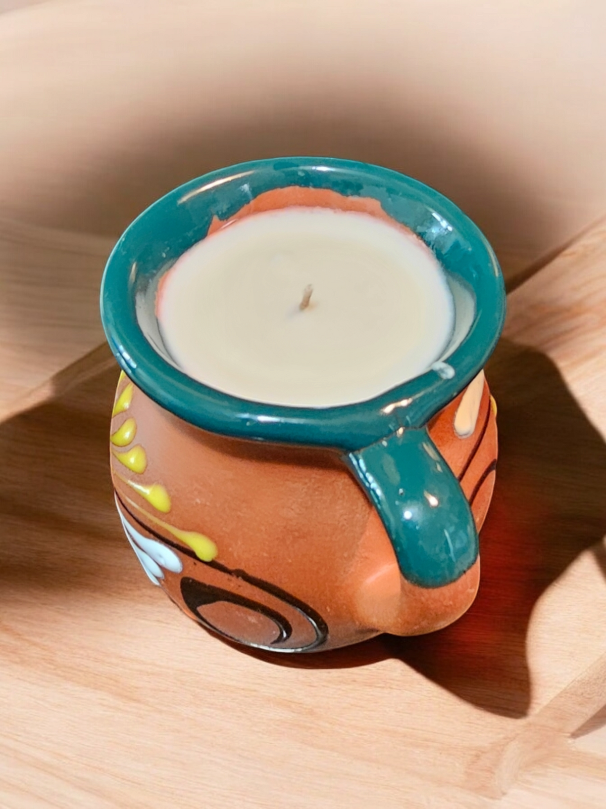 The Vela Lady handmade Mexican barro taza mug candle with soy wax in a traditional dark floral painted ceramic vessel.