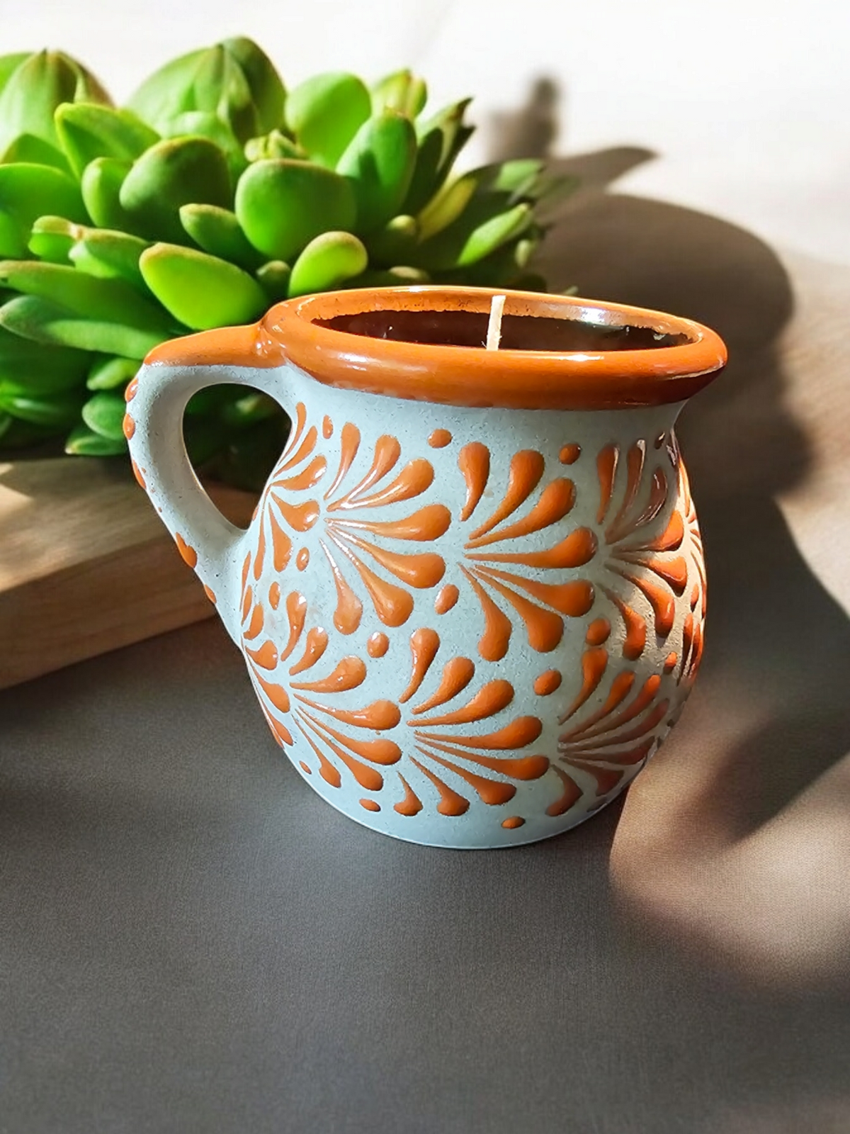 The Vela Lady orange and cream hand-painted Mexican barro mug candle with intricate floral patterns