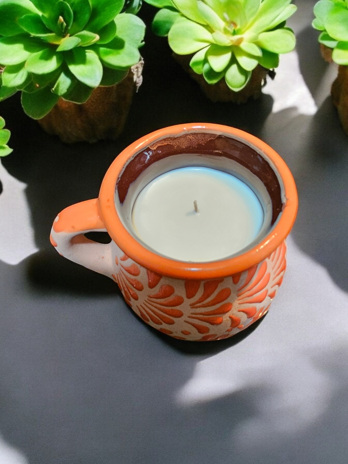 The Vela Lady orange handmade Mexican barro mug candle with soy wax, featuring intricate hand-painted floral patterns.