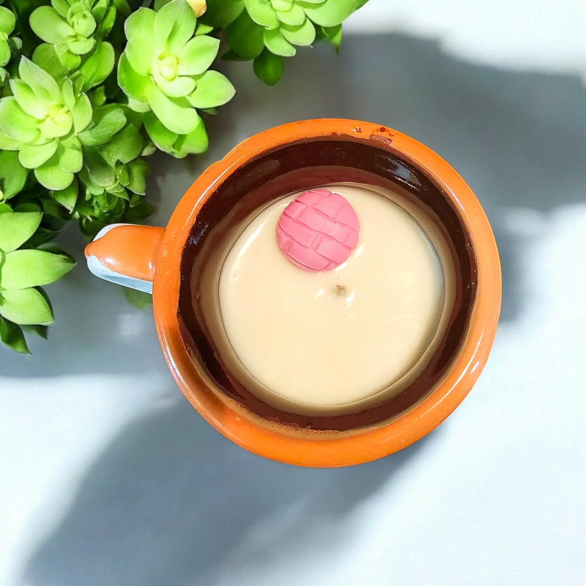 The Vela Lady orange handmade Mexican barro mug candle with soy wax and a decorative pink concha topper