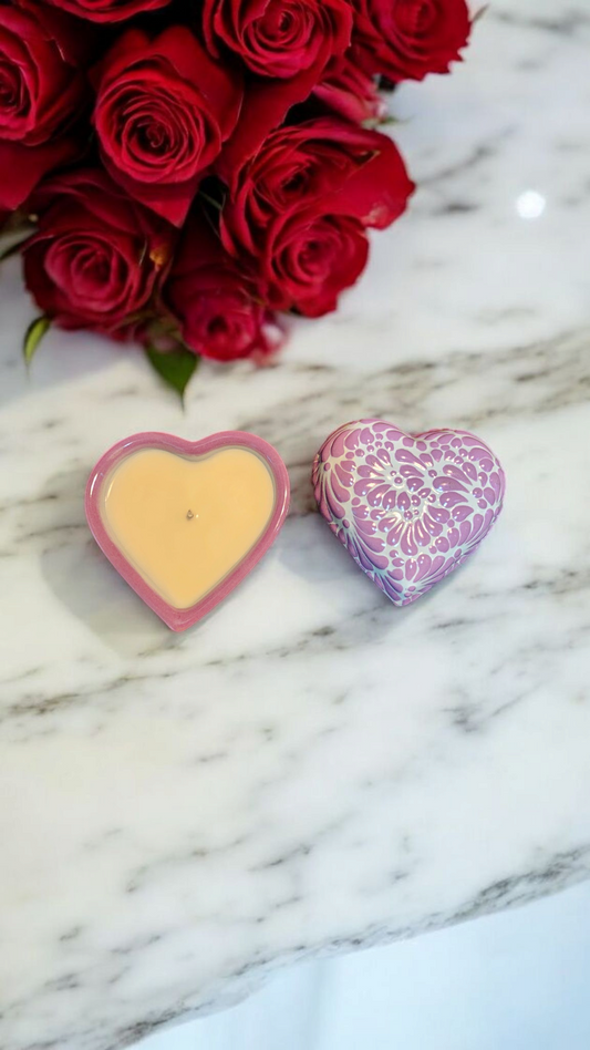 The Vela Lady heart-shaped purple Talavera ceramic candle and lid on a marble surface with red roses in the background.
