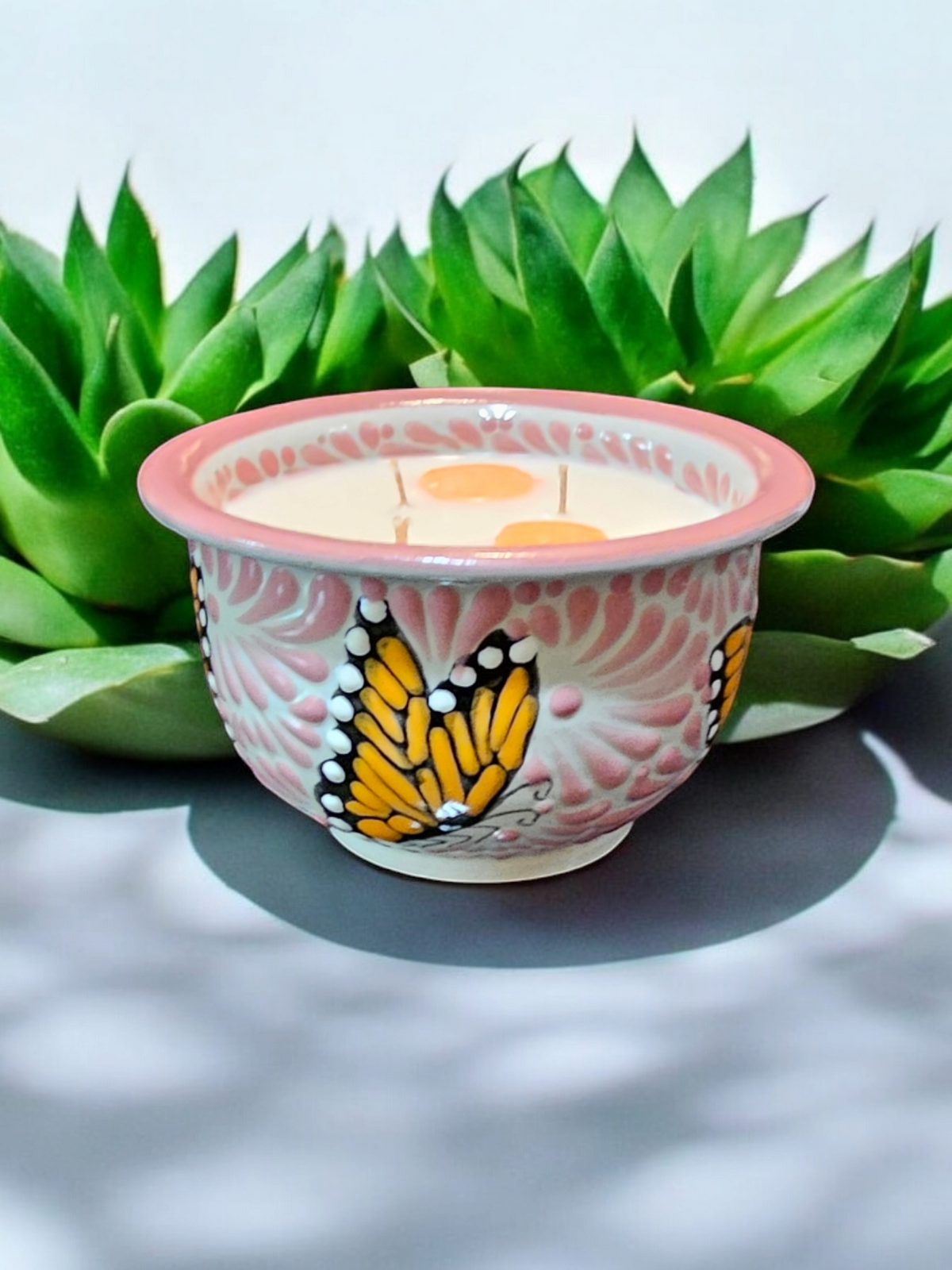 The Vela Lady pink and white Talavera salsa bowl candle featuring hand-painted butterfly designs and soy wax.