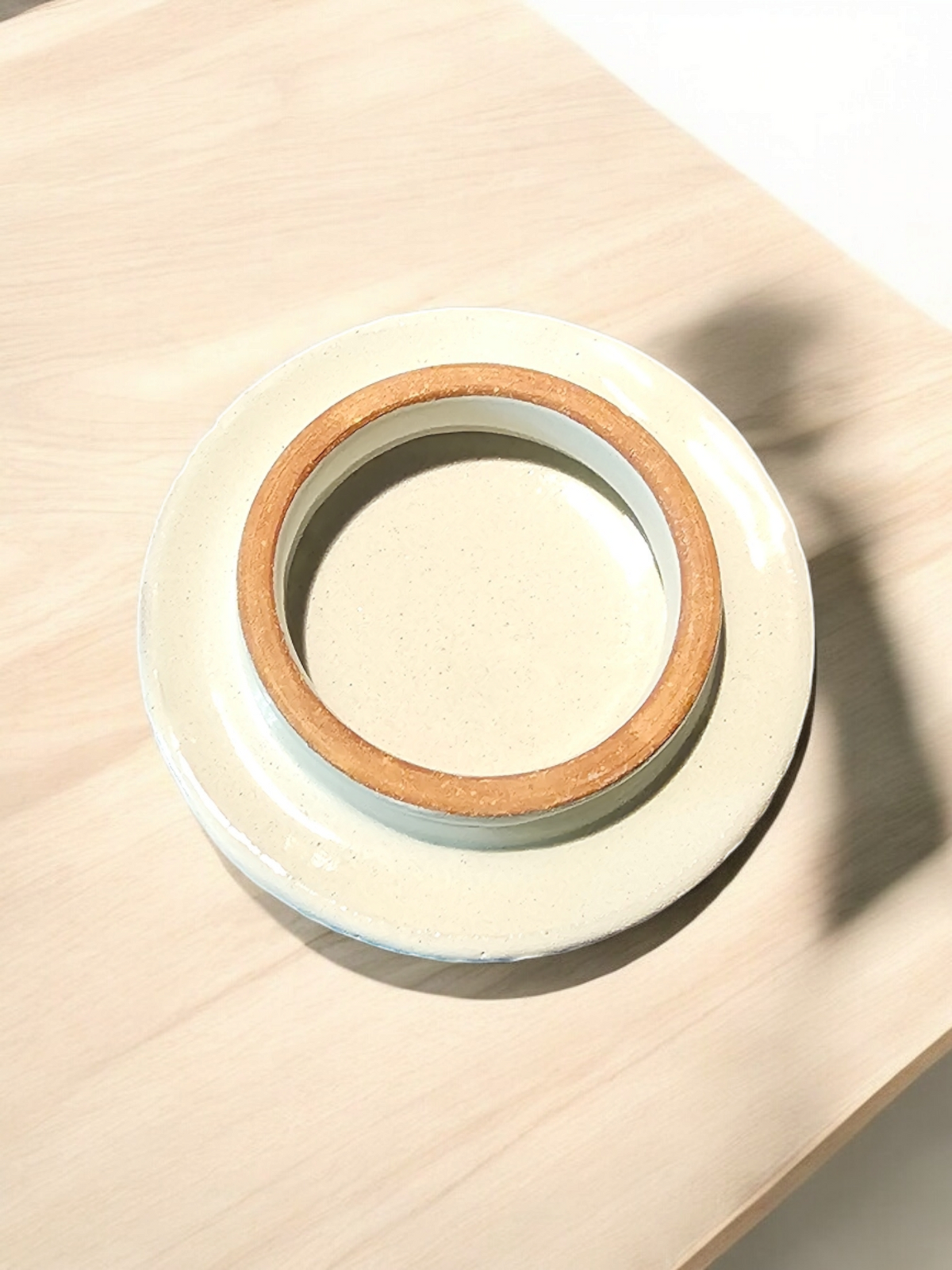 The Vela Lady Talavera candle vessel base showing the underside with a terracotta rim on a light wooden surface.