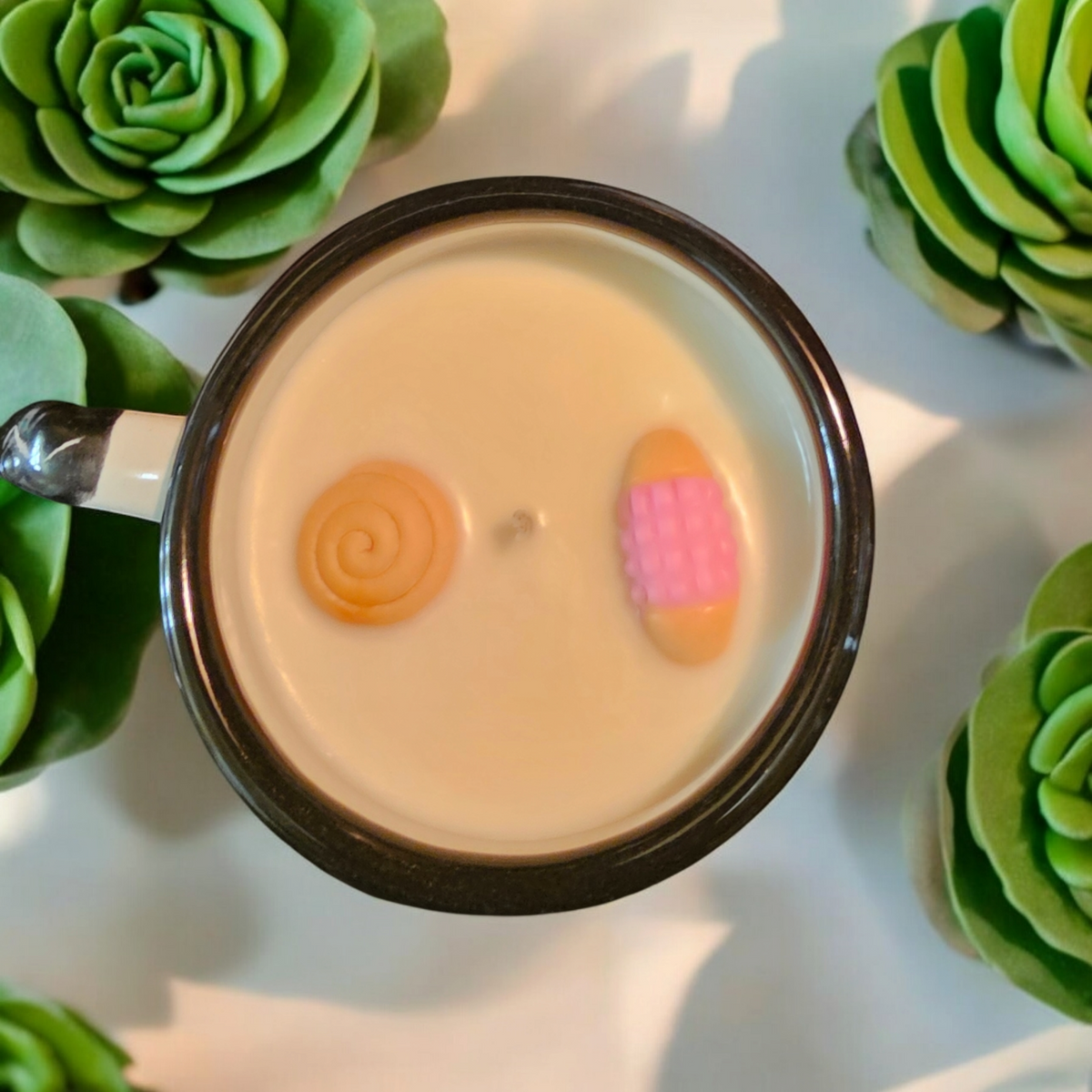 The Vela Lady La Catrina Talavera mug candle with soy wax and decorative wax toppers, surrounded by faux succulents.