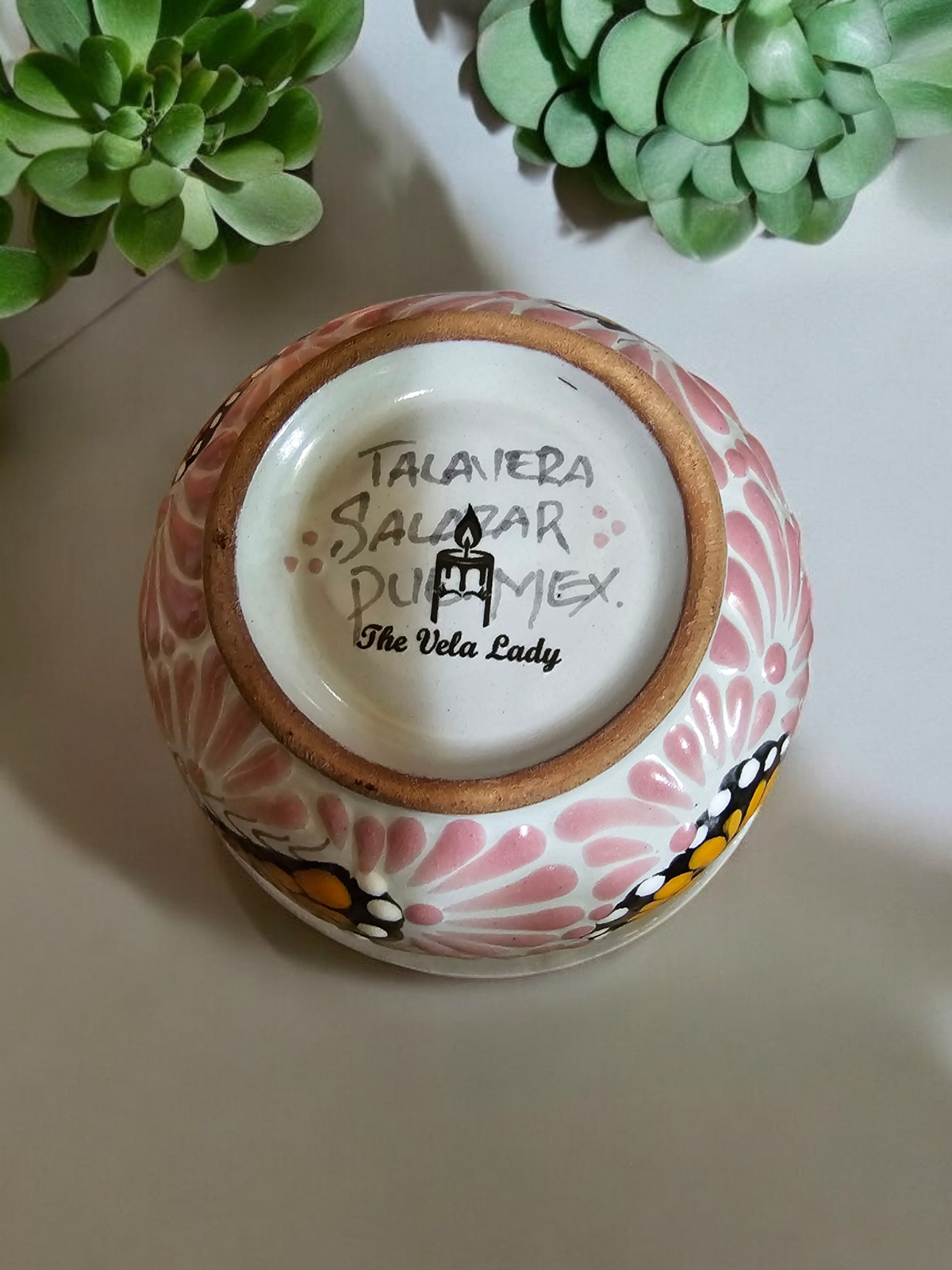 The Vela Lady handcrafted pink and white Talavera salsa bowl candle with butterfly detail, viewed from the bottom.